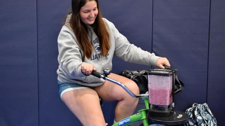 Penn State DuBois student Aleigha Geer pedals the smoothie bike during the 2023 Earth Day celebration at the PAW Center.